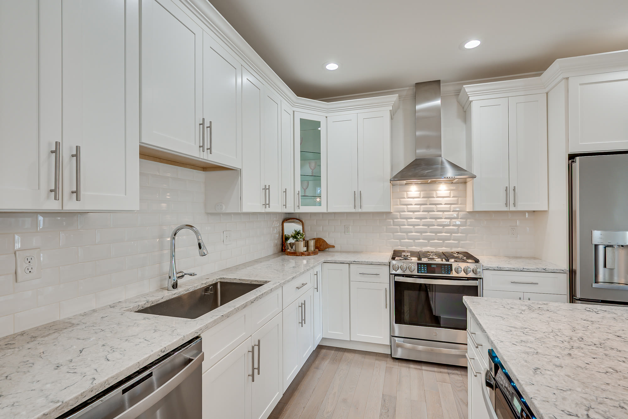 Kitchen with white shaker cabinetry, quartz counters and a stainless gas range